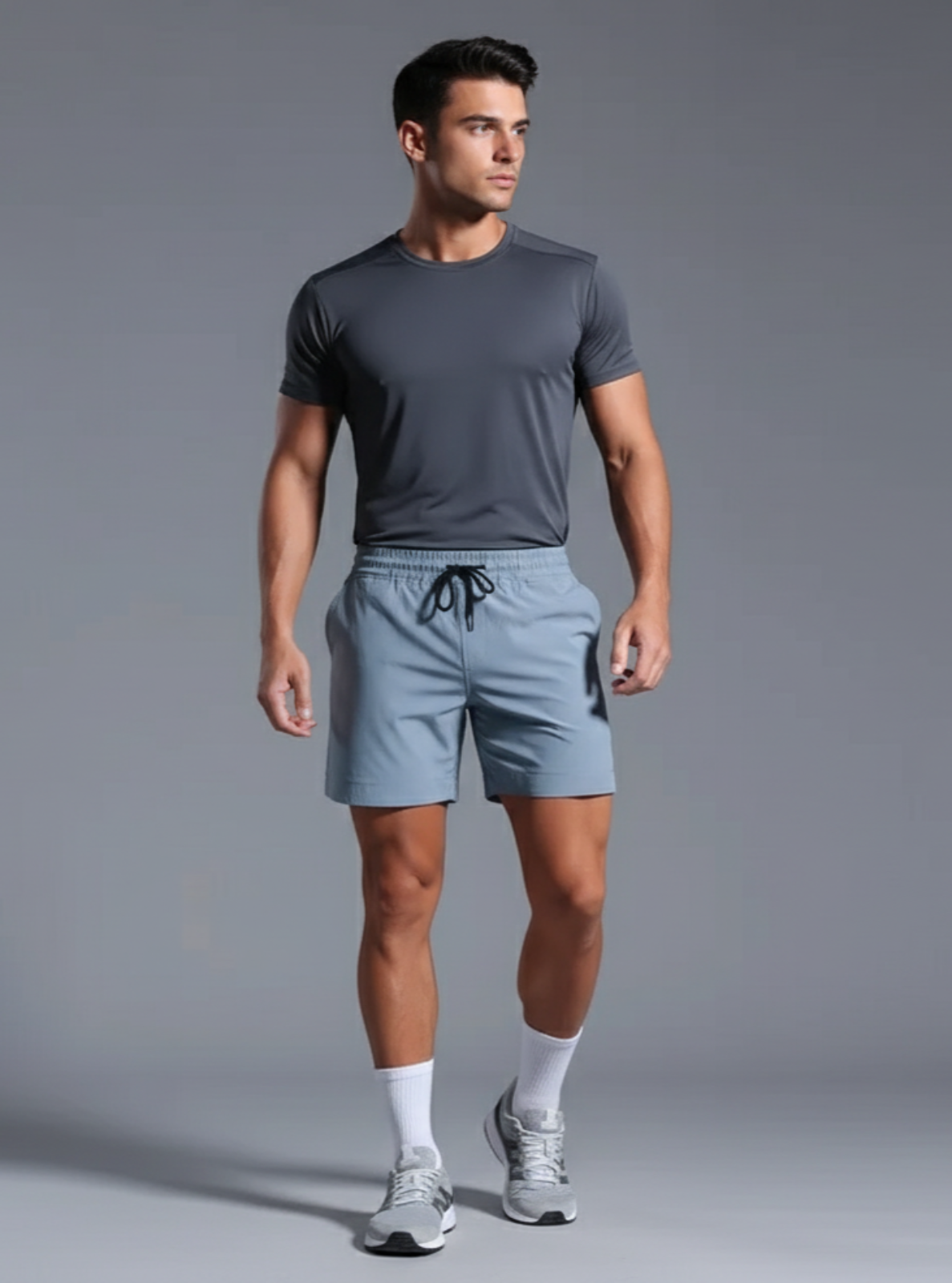 Man wearing a gray t-shirt and light blue shorts on a gray background