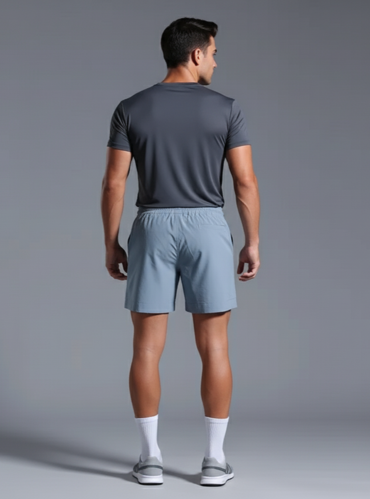 Man wearing a gray t-shirt and light blue shorts on a gray background