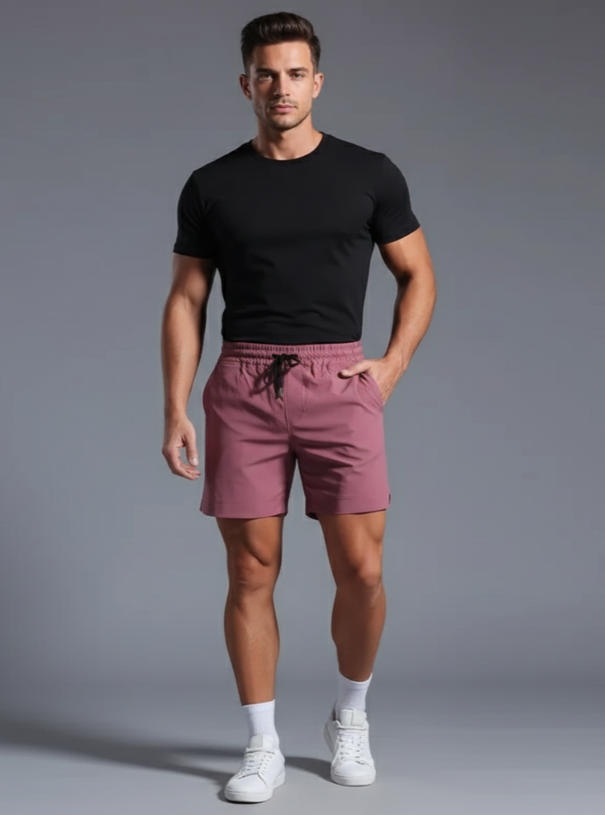 Man wearing a black t-shirt and pink shorts on a gray background