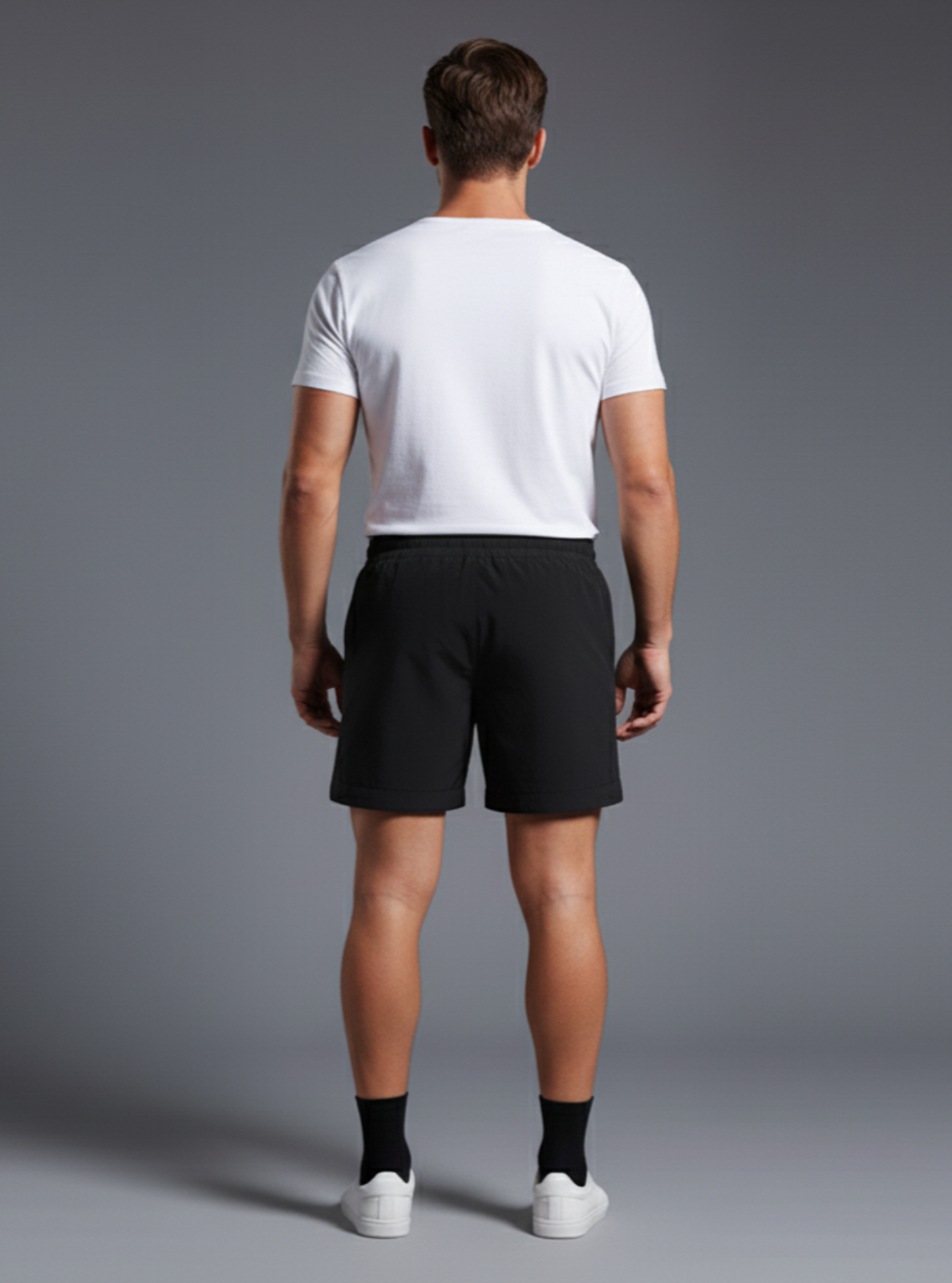 Man wearing a white t-shirt and black shorts on a gray background