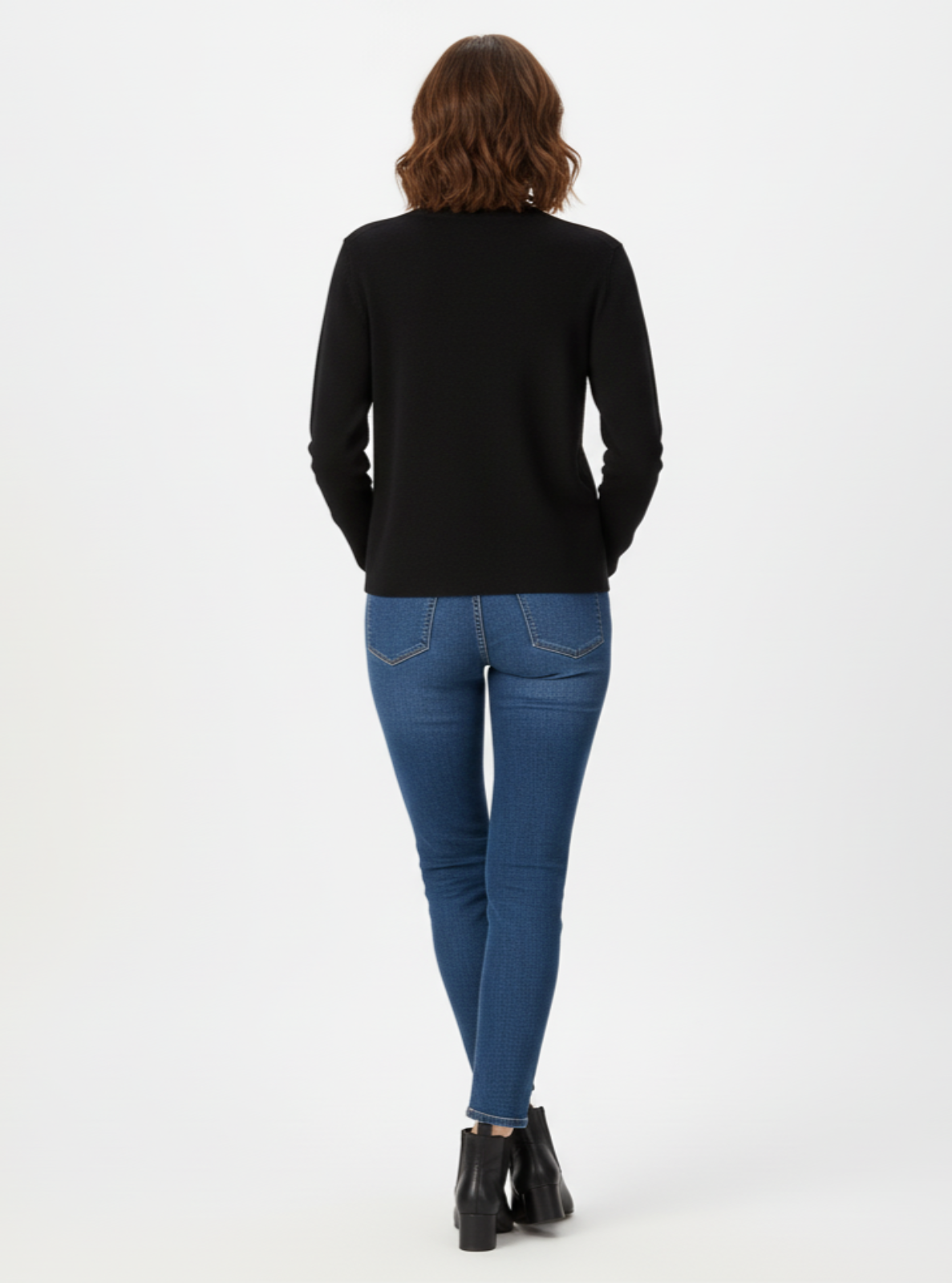 Person wearing a black top and blue jeans on a white background
