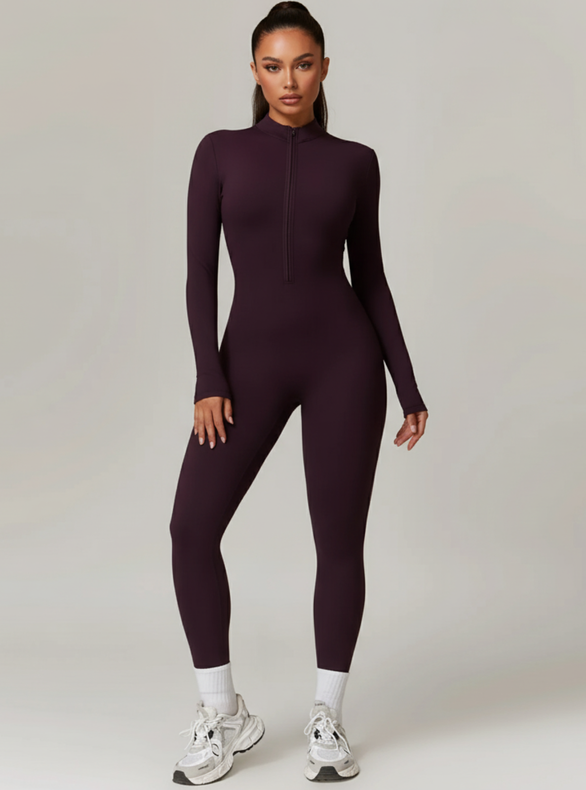 Woman wearing a purple jumpsuit on a plain background