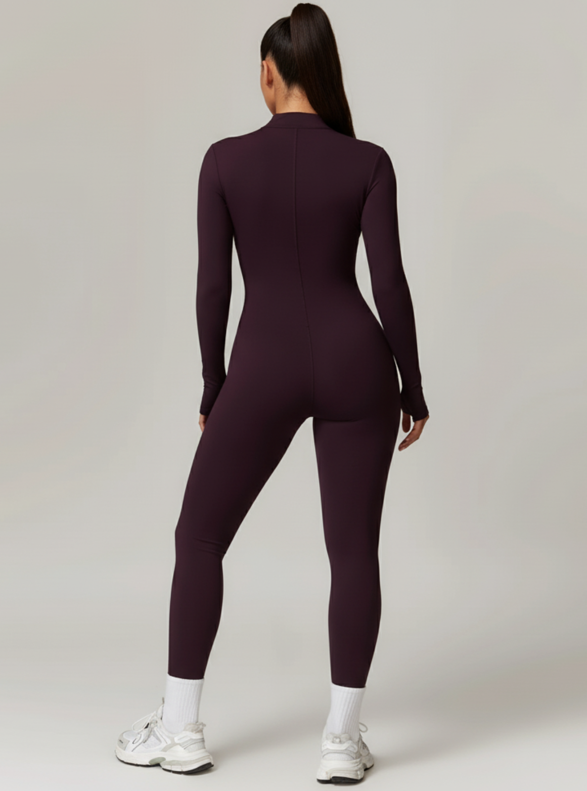 Person wearing a dark purple bodysuit on a light gray background