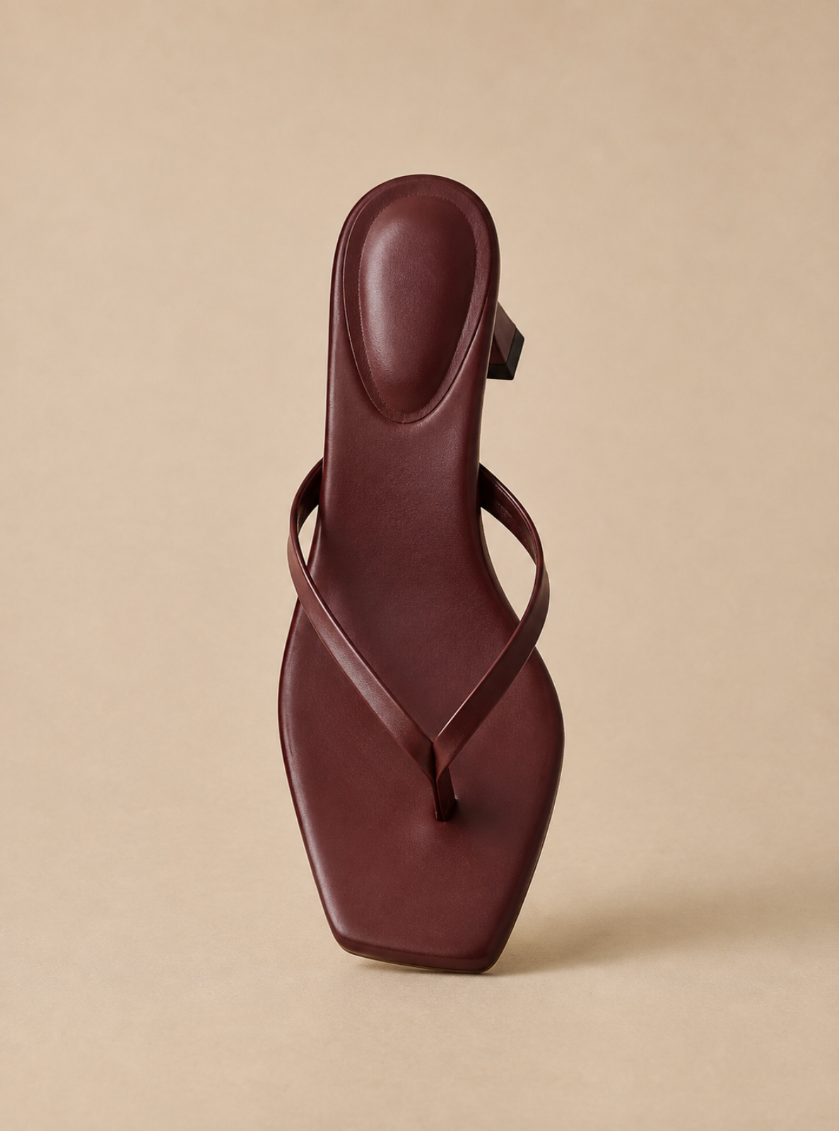 A single dark burgundy leather thong sandal with a square toe and block heel, shown from a top-down perspective on a solid beige background.