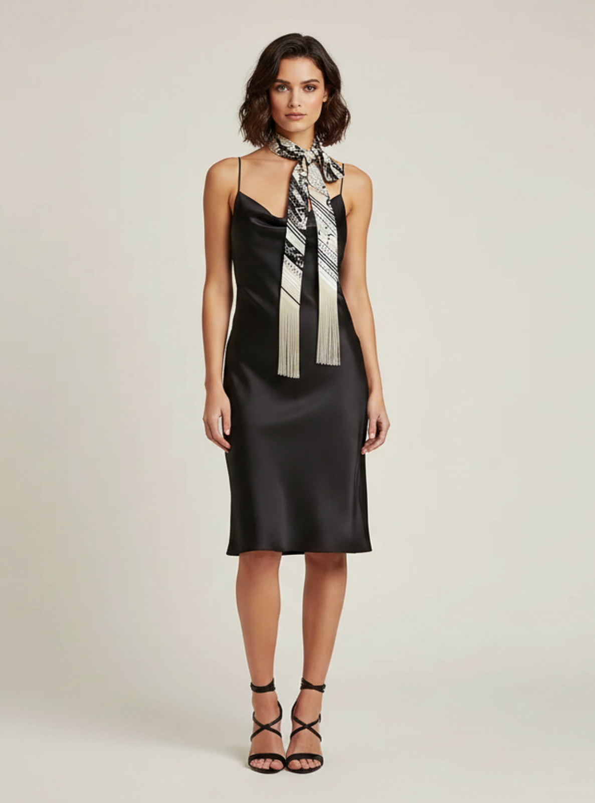 Woman wearing a black dress with a scarf on a plain background