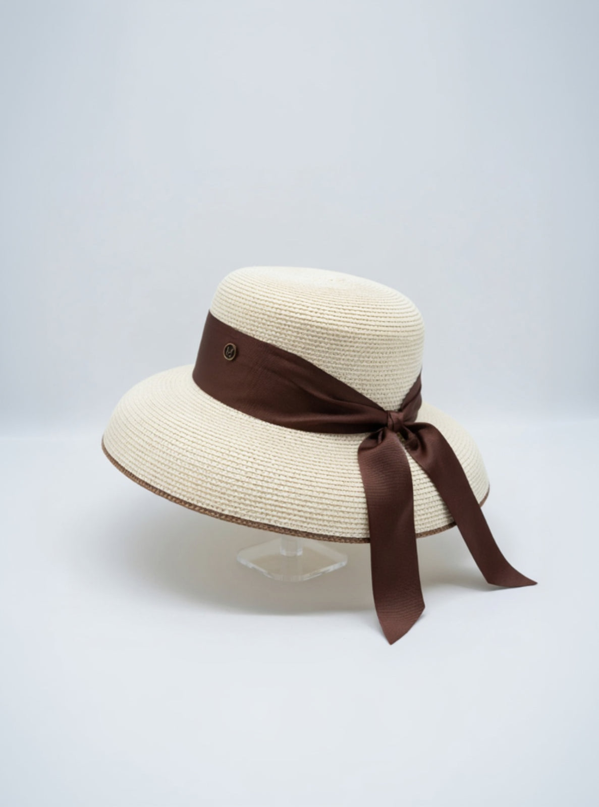 Beige straw hat with a brown ribbon on a light gray background