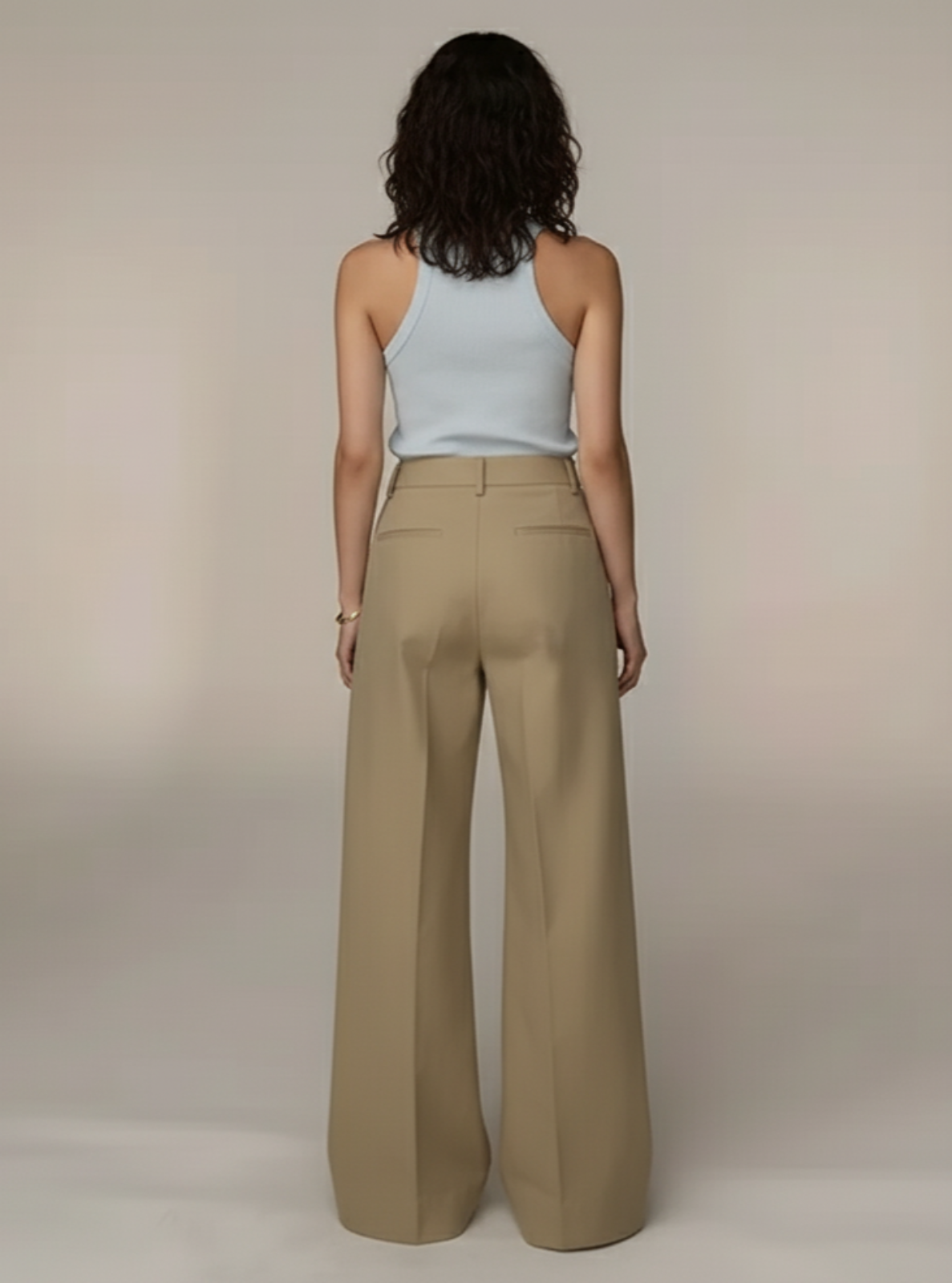 Woman wearing beige wide-leg pants and a light blue top against a plain background