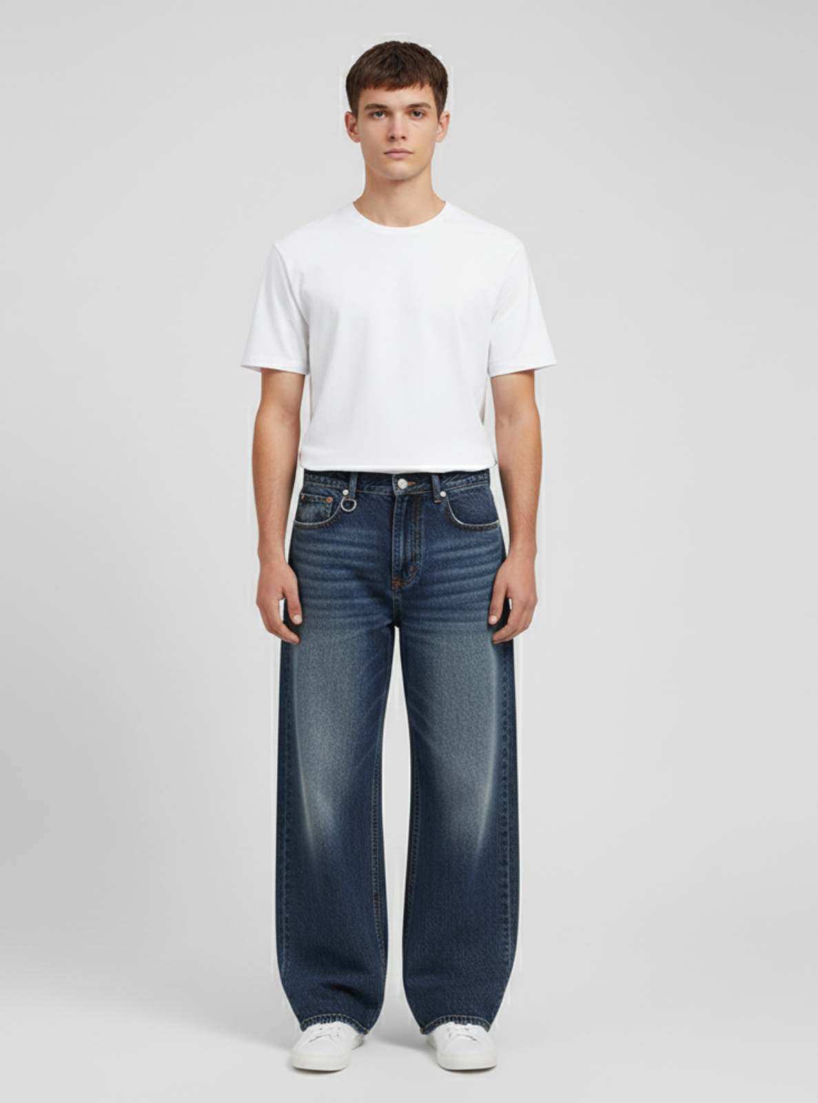 Person wearing a white t-shirt and blue jeans on a plain background