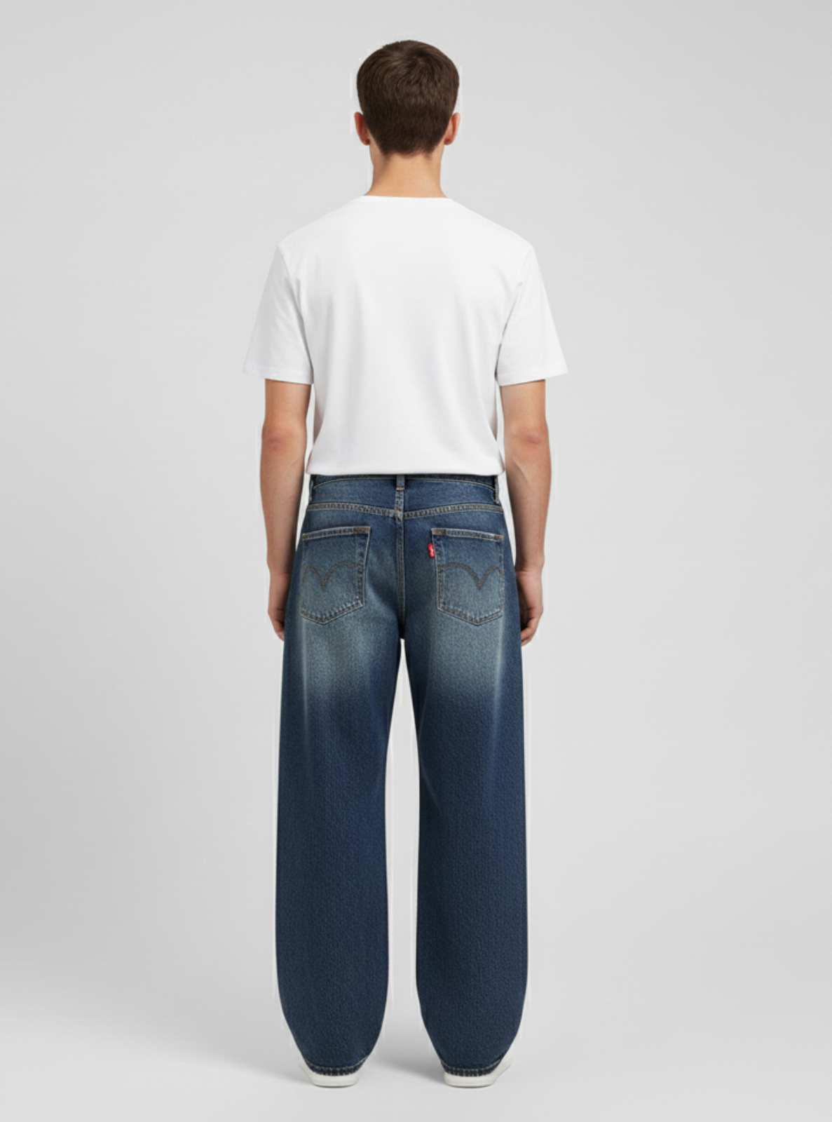 Person wearing blue jeans and a white t-shirt on a gray background