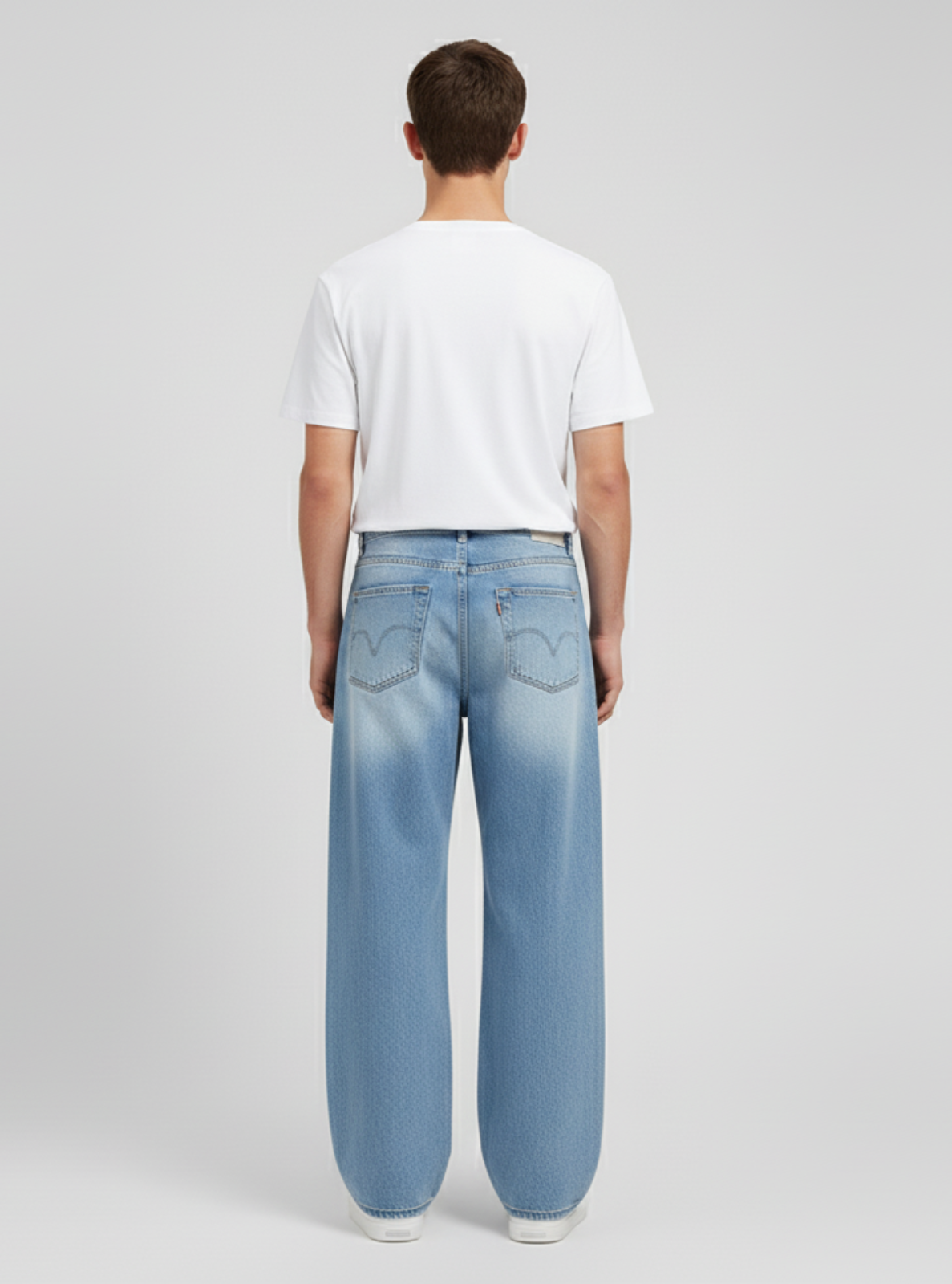 Person wearing light blue jeans and a white t-shirt on a plain background