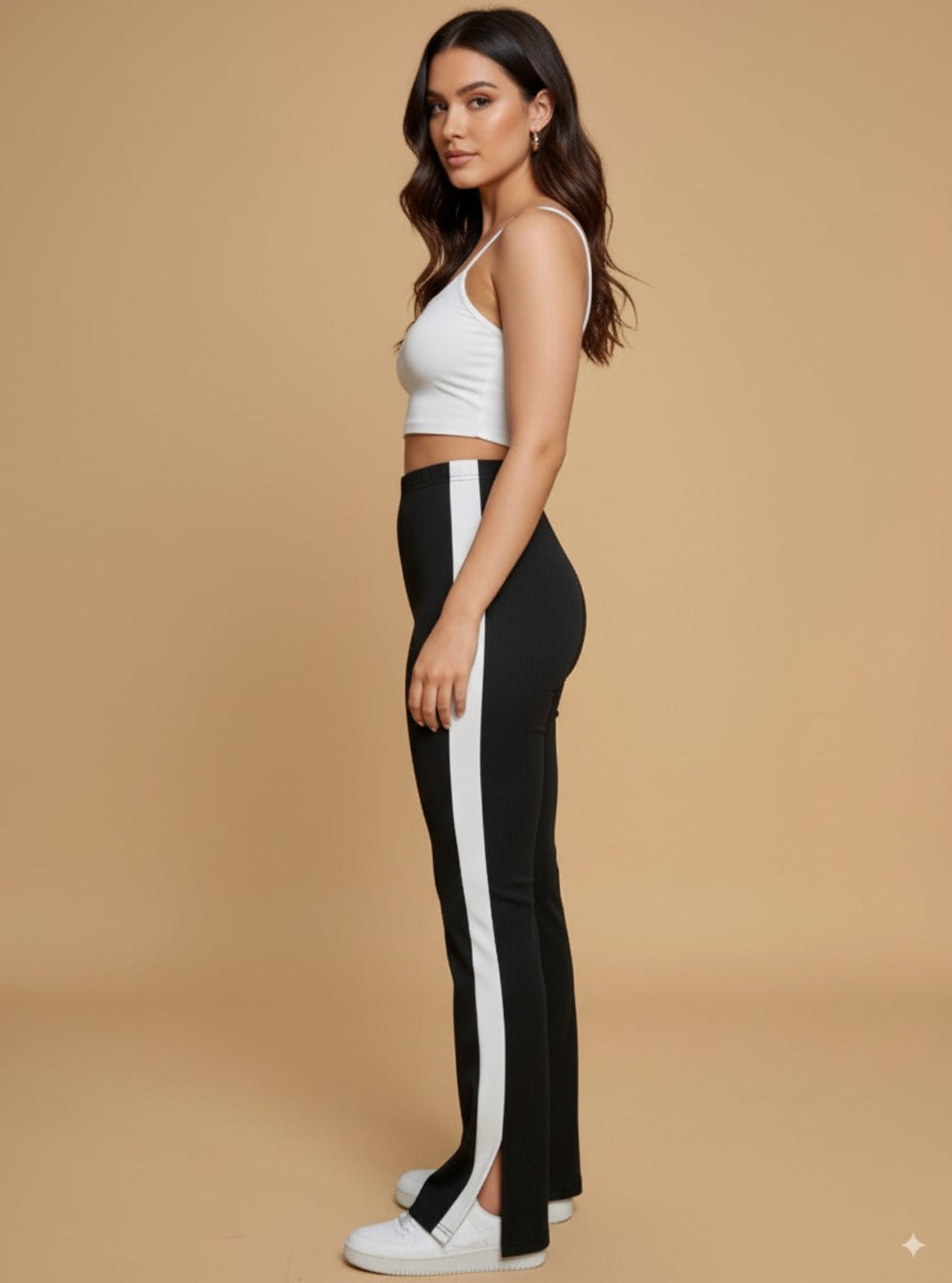 Woman wearing a white crop top and black pants with a white stripe on a beige background