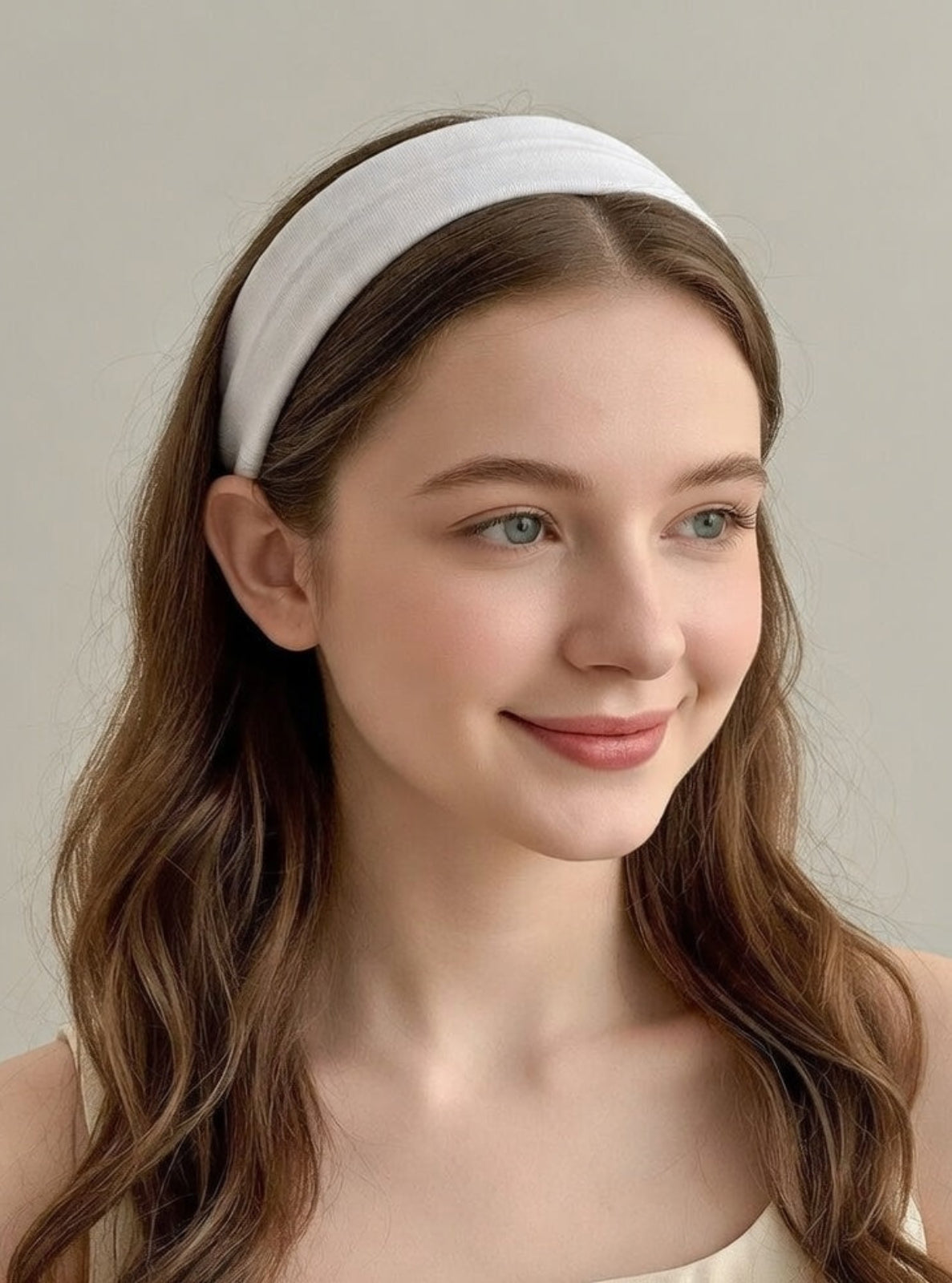 Woman wearing a white headband against a plain background