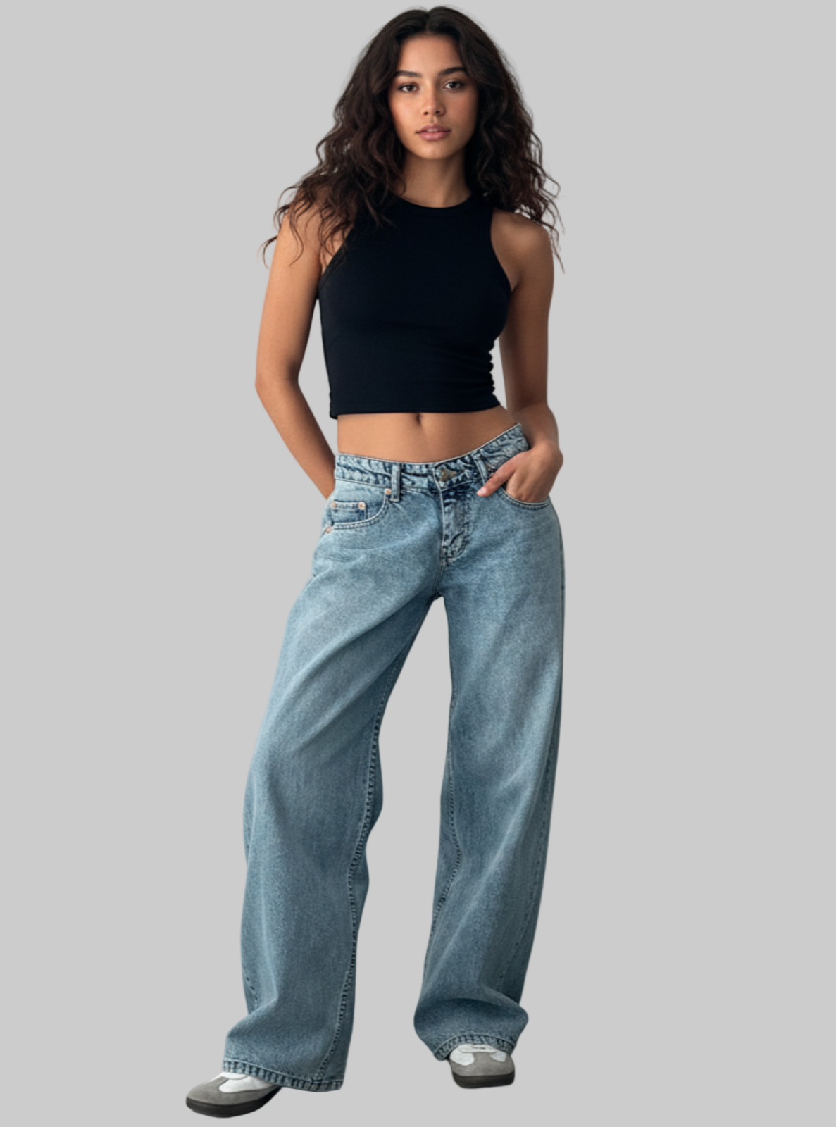 Woman wearing a black crop top and blue jeans against a plain background