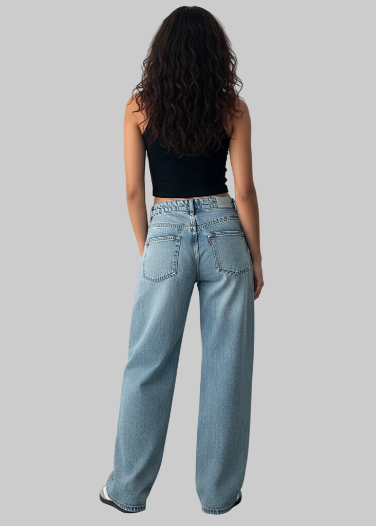 Person wearing light blue jeans and a black top against a plain background