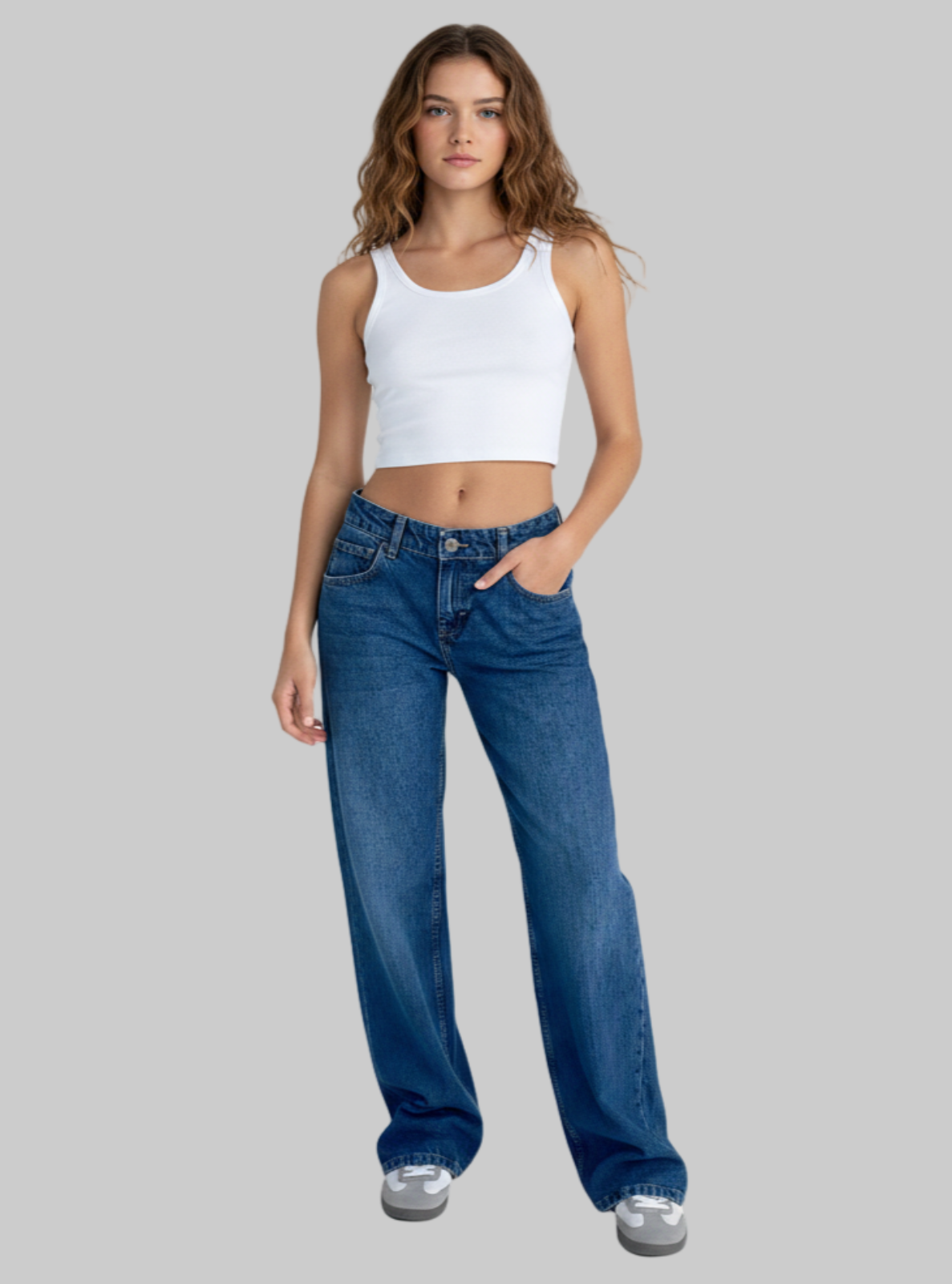 Woman wearing a white tank top and blue jeans on a white background