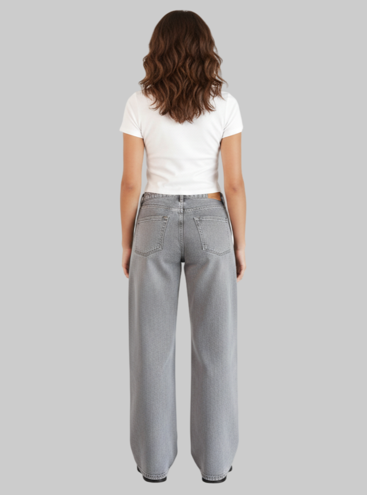 Person wearing gray jeans and a white shirt on a white background