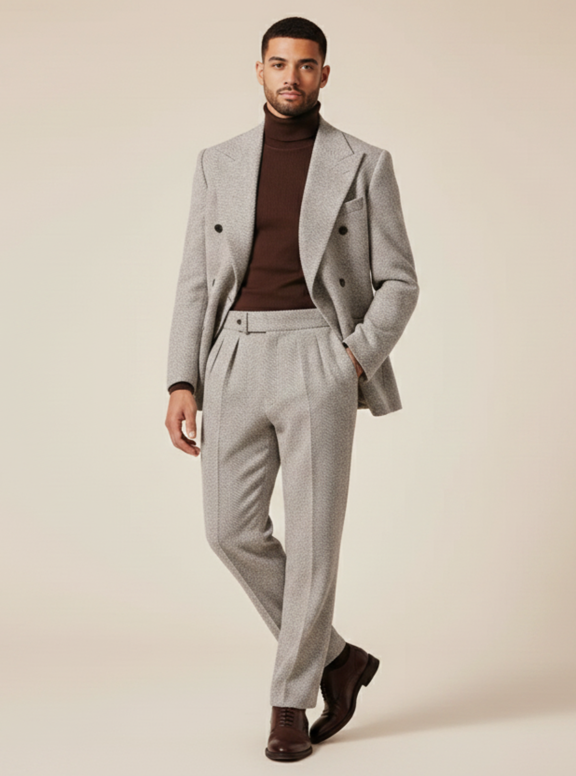 Man wearing a gray suit with a brown turtleneck against a beige background