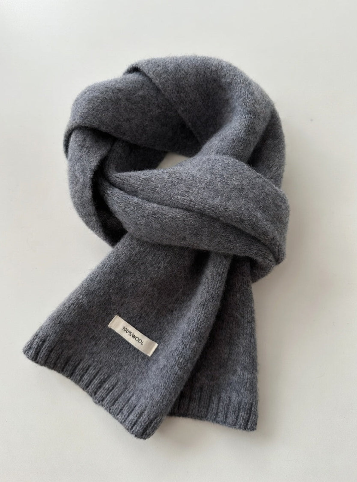 Gray scarf with a brand label on a light gray background