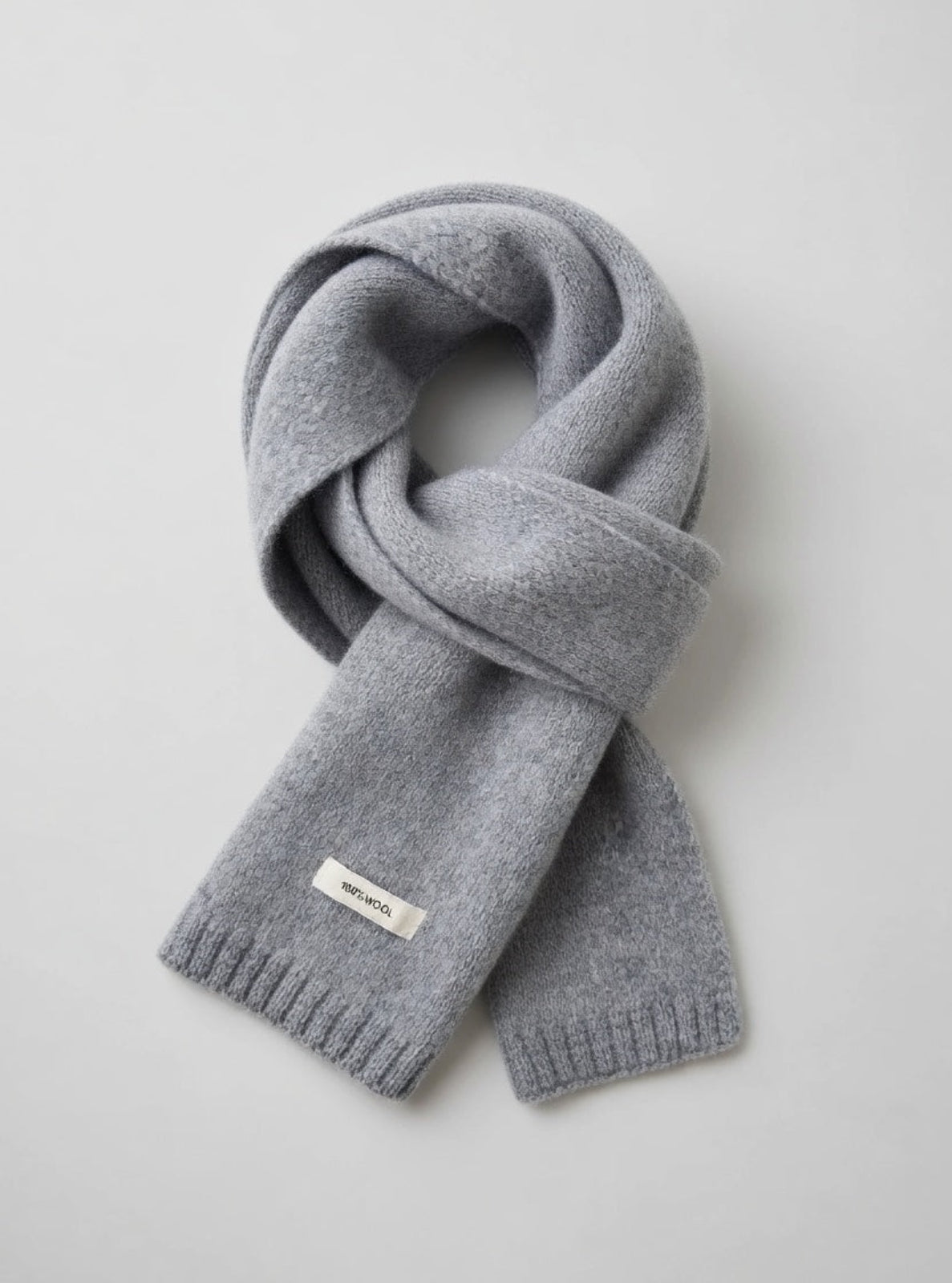 Gray knit scarf with a brand label on a light gray background