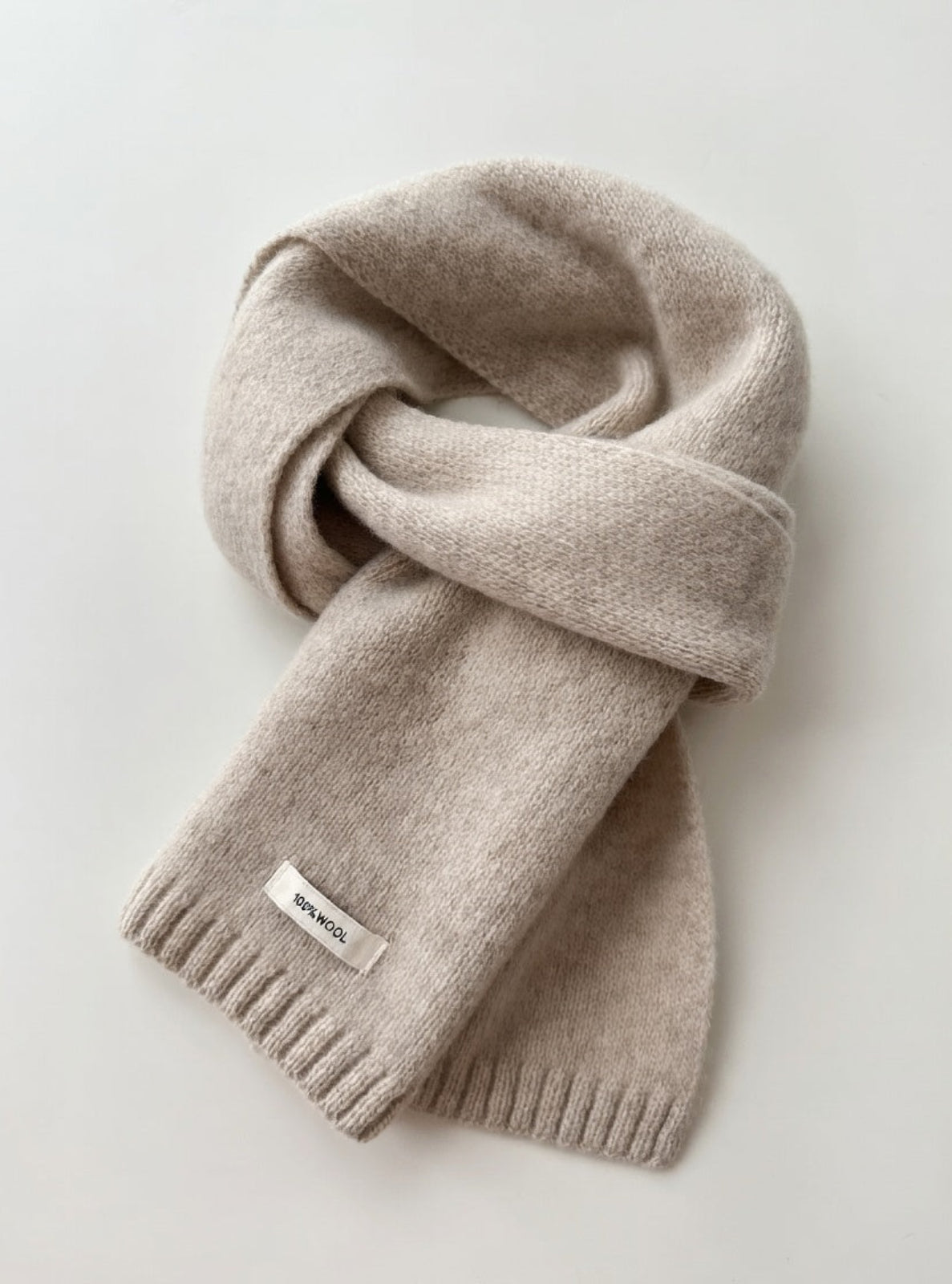 Beige scarf with a brand label on a light gray background