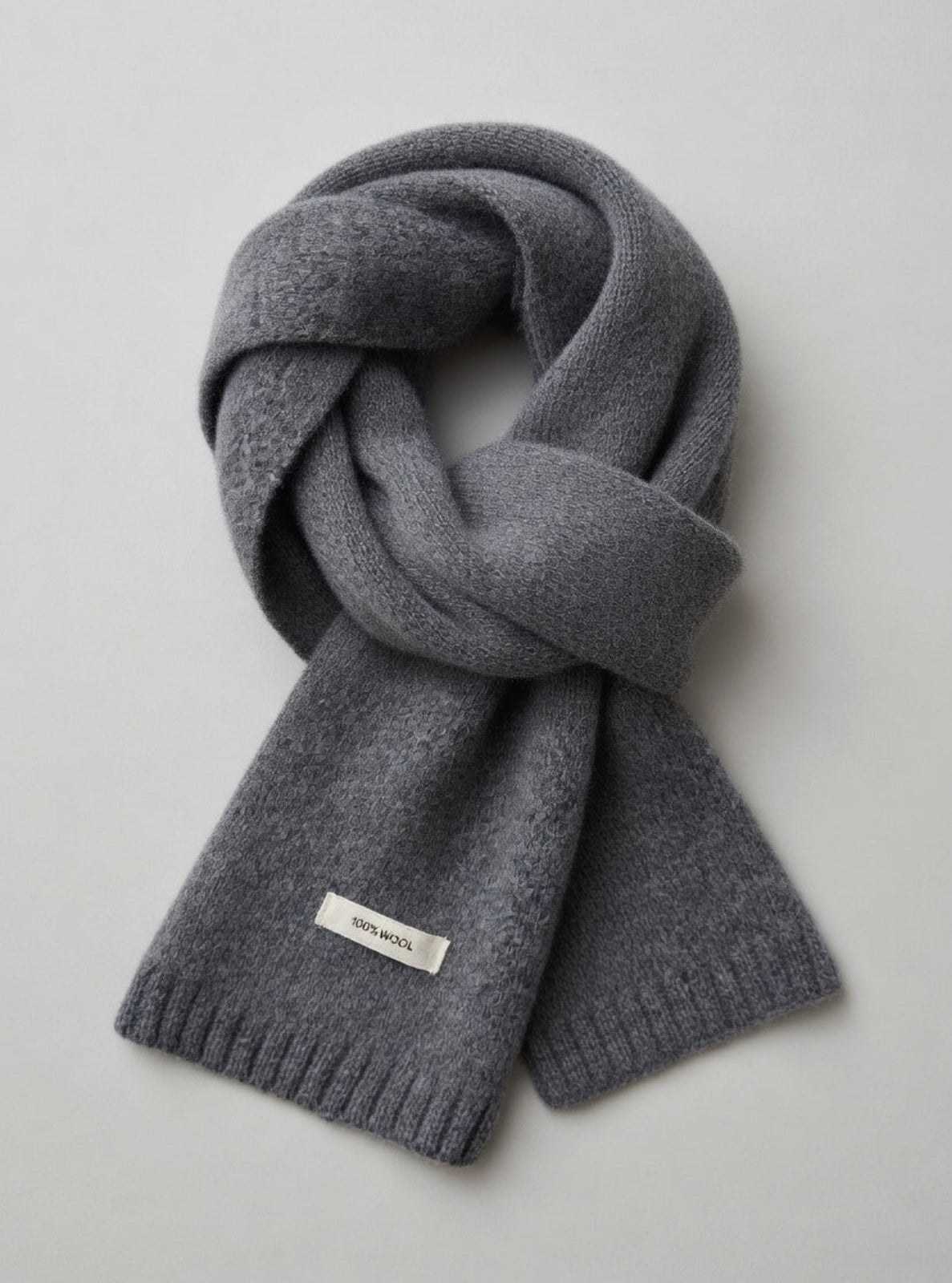 Gray knit scarf with a brand label on a light gray background