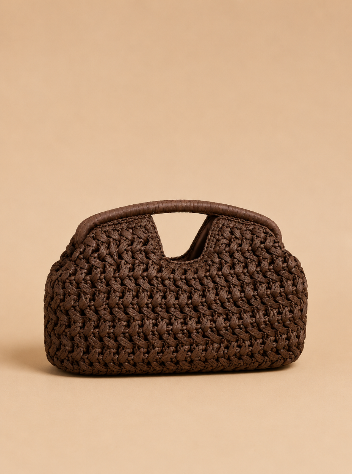 A dark brown woven straw handbag with a top handle, photographed against a solid beige background.