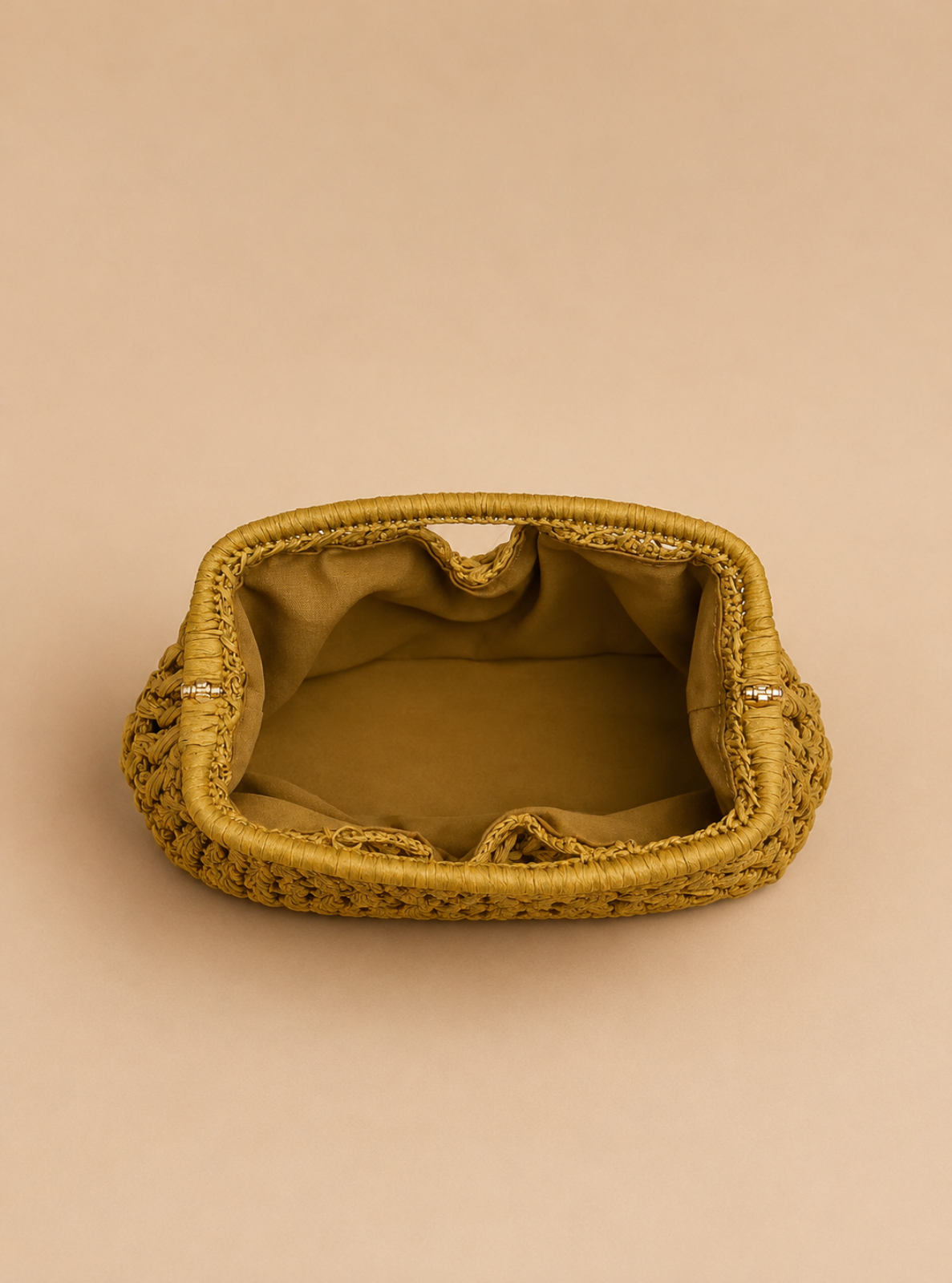 A small woven clutch bag in a mustard yellow color, shown from a top-down view on a solid beige background.