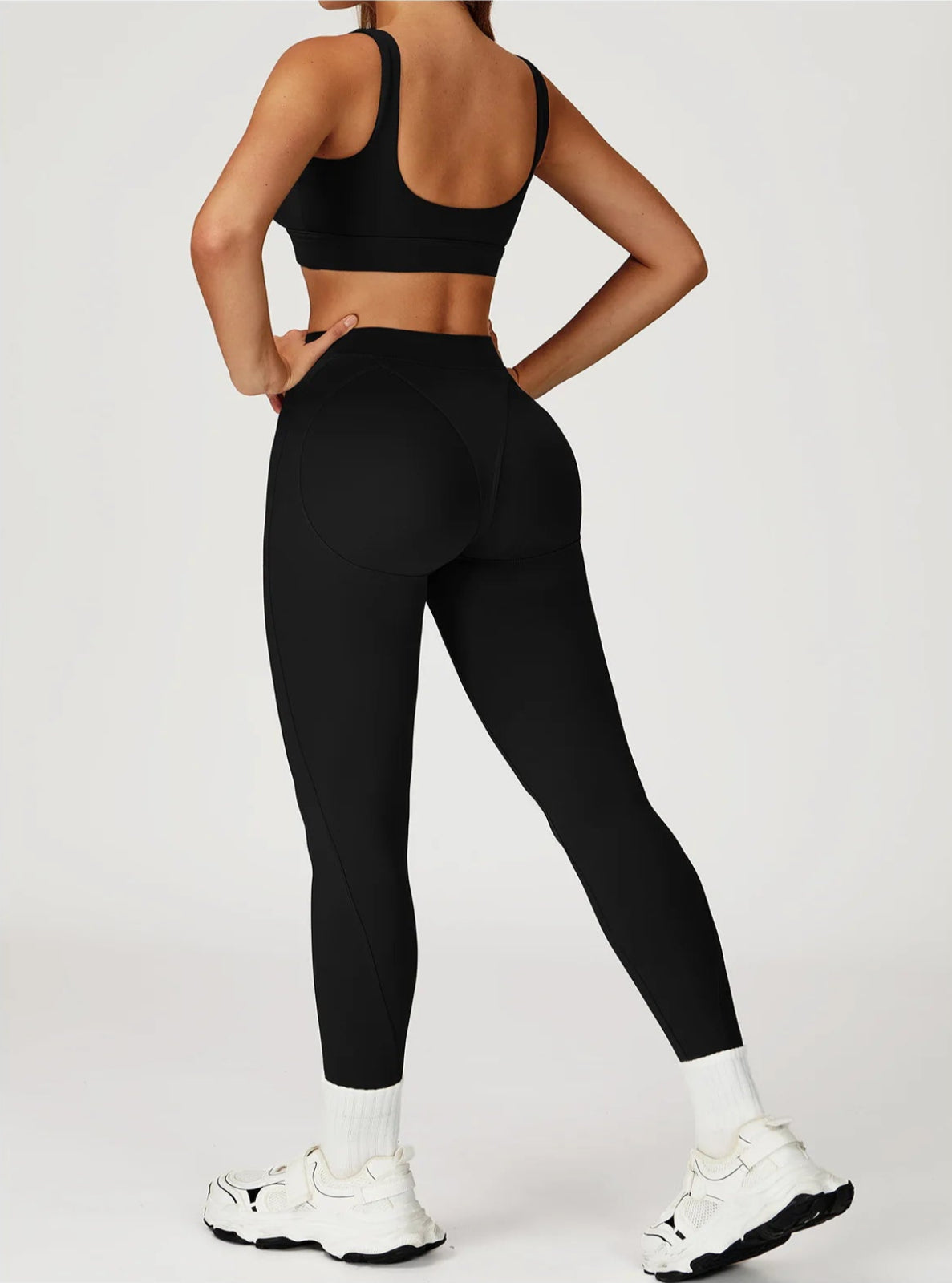 Person wearing black athletic leggings and sports bra on a white background