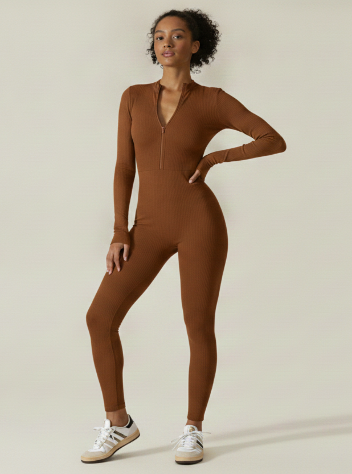 Woman wearing a brown bodysuit on a beige background