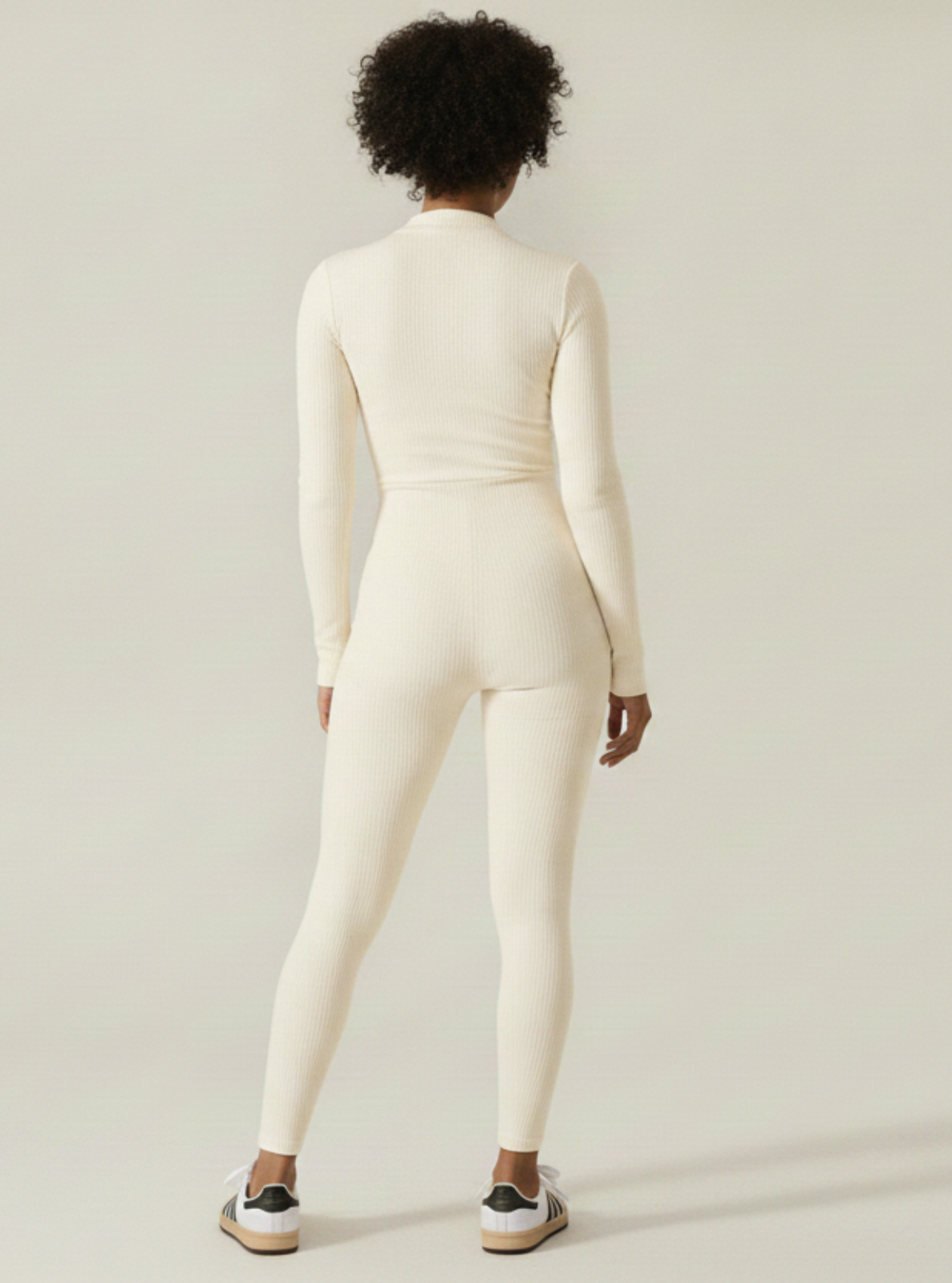 Person wearing a white bodysuit against a plain background