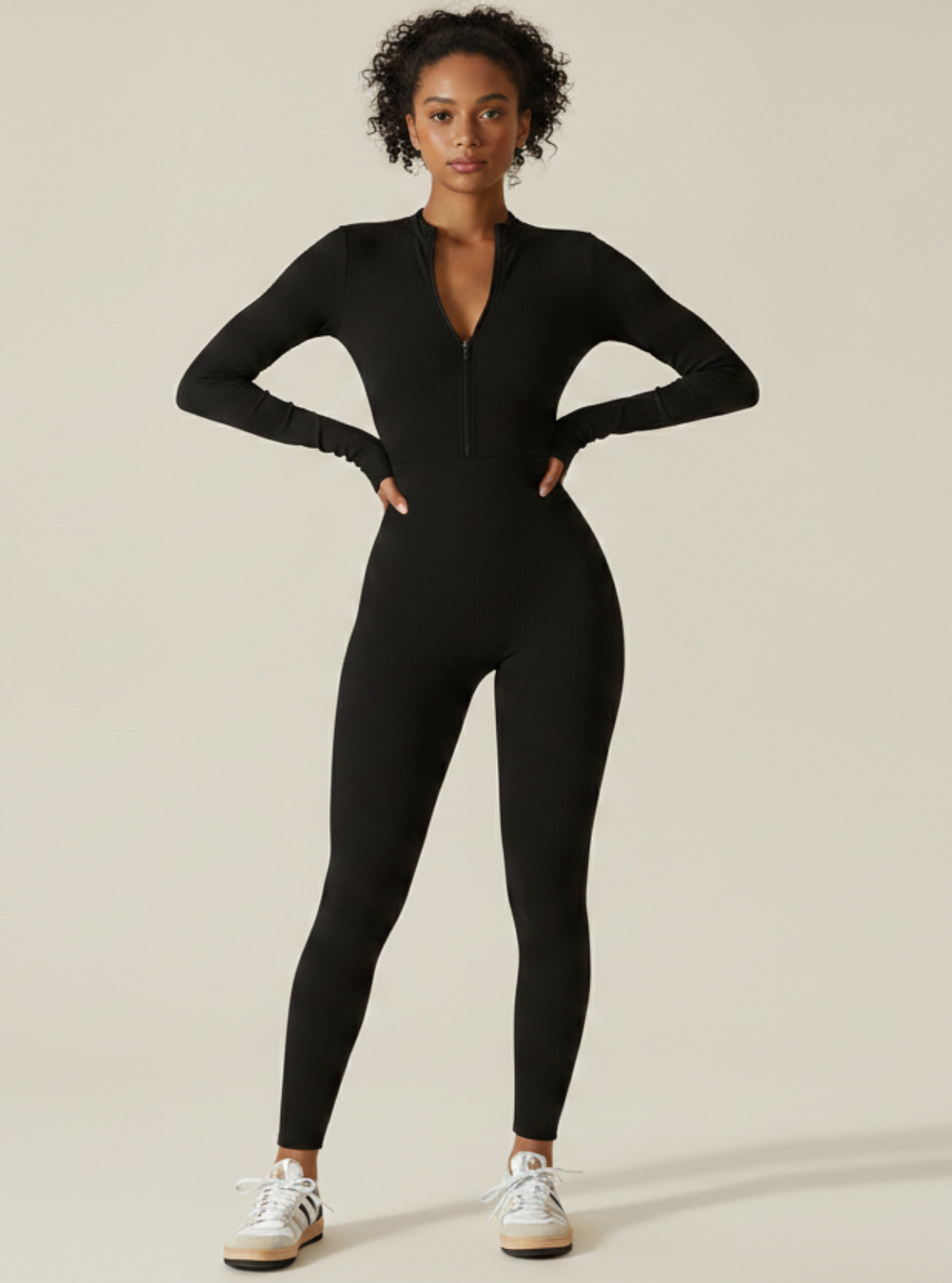 Person wearing a black jumpsuit on a beige background