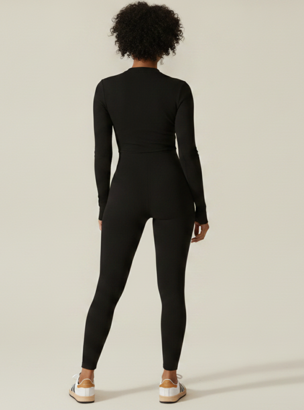 Person wearing a black jumpsuit on a plain background