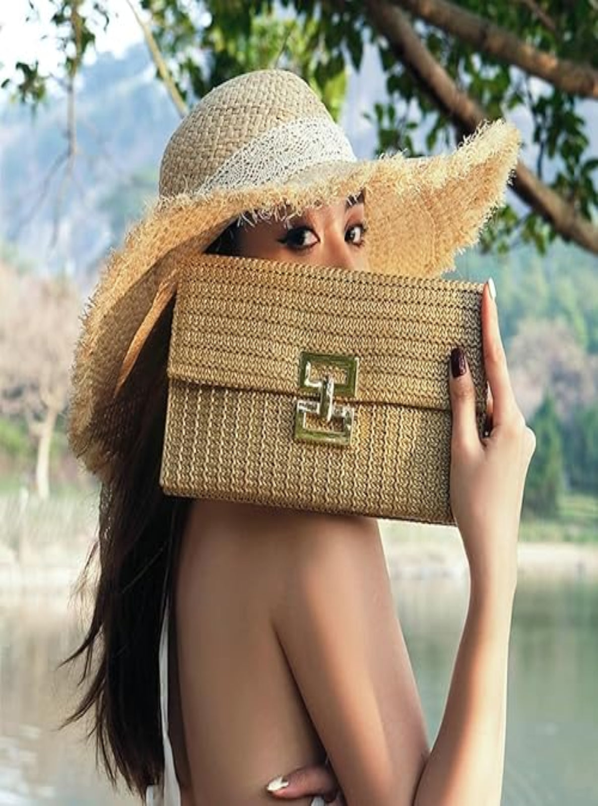 Woman holding a straw handbag with a scenic background